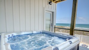 Un bain à remous sur une terrasse en bois, avec vue sur l’océan.