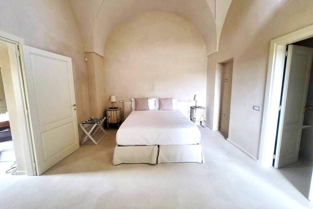 Un dormitorio amplio con una cama grande, una mesita de noche pequeña y una silla.
