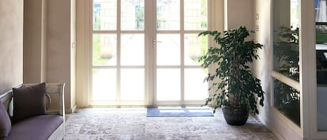 Una habitación amplia con un techo alto abovedado, un gran arco de entrada y una planta en maceta.