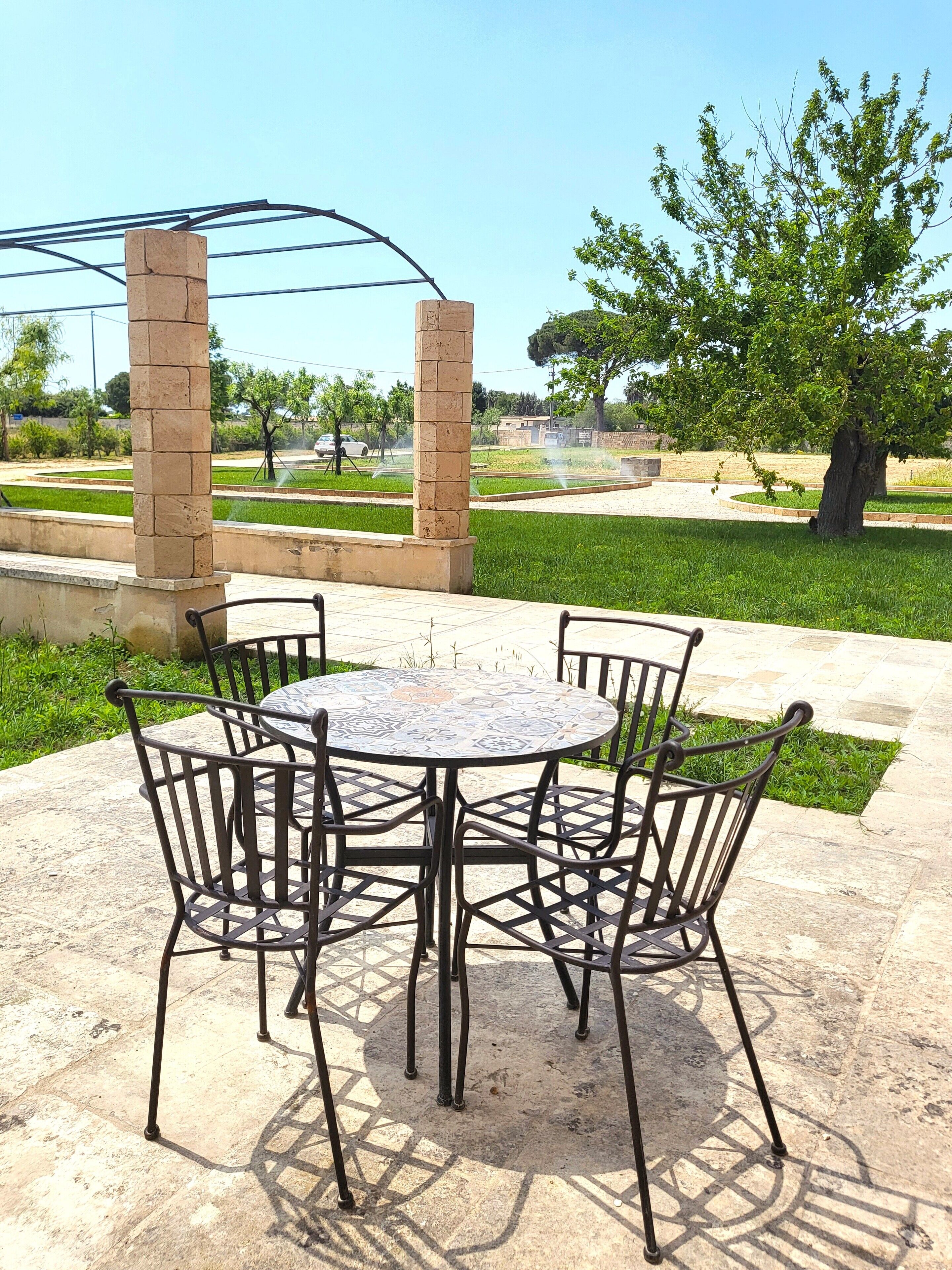 A round metal table with chairs, surrounded by a stone patio.