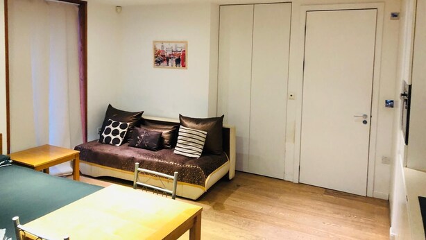 A small, well-lit room with a sofa, a wooden table, and a door.