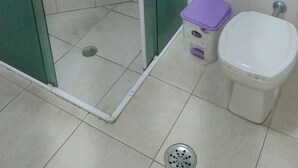Un baño con ducha de vidrio, inodoro y un pequeño cubo de basura.