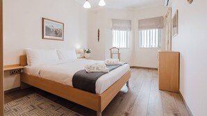 A neatly arranged bedroom with a bed, bedside table, lamp, and a small wardrobe.
