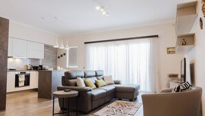 A modern living room with a sectional sofa, a small round table, and a kitchen area with a built-in island.