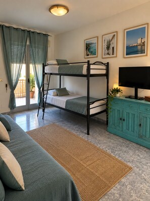 A room with bunk beds, a television, a cabinet, and a window with curtains.