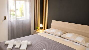 A hotel room with a bed, a bedside lamp, a wall-mounted decorative item, and a window with curtains.
