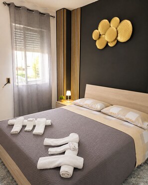 A hotel room with a bed, a bedside lamp, a wall-mounted decorative item, and a window with curtains.