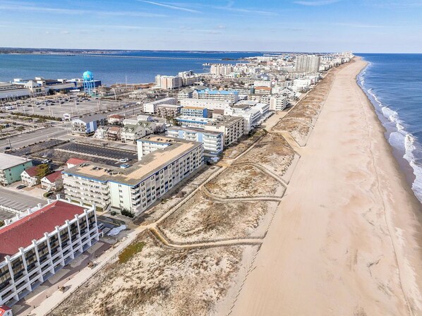 A coastal cityscape with a beachfront hotel, a water tower, and a long pier extending into the sea. - Very spacious 2 bedroom oceanfront condo building with free WiFi, suede furniture, with a limited ocean view on the first floor, in exciting downtown only steps to the beach and 10 blocks to the end of the boardwalk. (Ocean City)