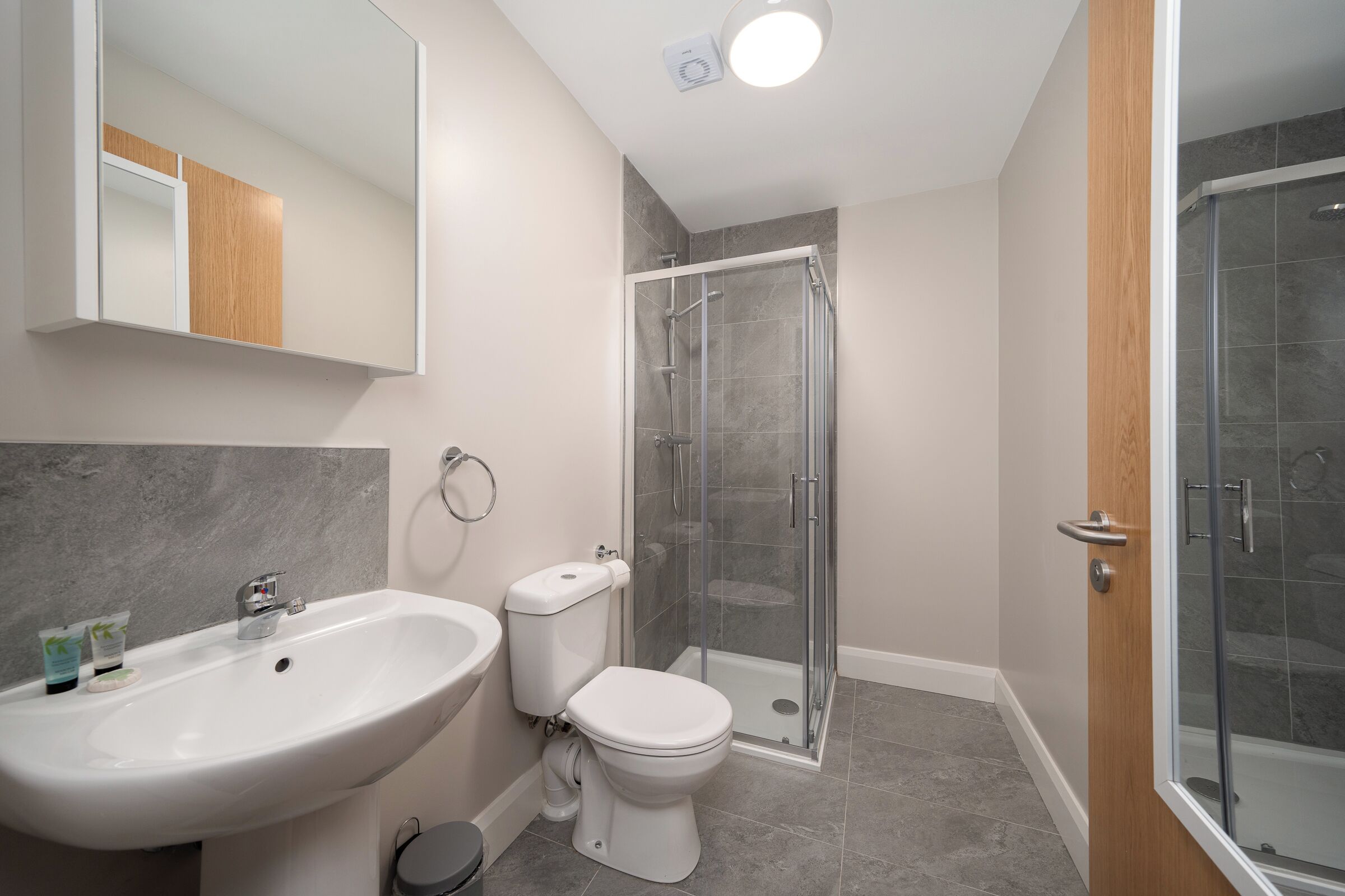 Un baño con lavamanos, inodoro y cabina de ducha de vidrio.