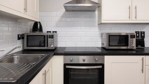 Una cocina moderna con dos microondas integrados, una campana extractora de acero inoxidable y un horno empotrado.