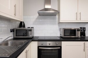 Una cocina moderna con dos microondas integrados, una campana extractora de acero inoxidable y un horno empotrado.