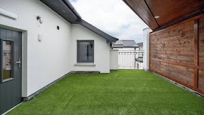 Una casa moderna con fachada blanca, cerca de madera y césped cuidado.