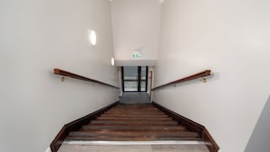 Una escalera de madera con barandales que conduce a una puerta con un letrero verde encima.