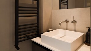 A modern bathroom with a white sink, two faucets, a black towel rack, and a large mirror. - Sophisticated Notting Hill 2bed (London)