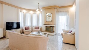 A living room with a flat-screen TV, two sofas, a coffee table, and a fireplace. - Villa Amare - Heraklion Private Garden Retreat (Hersonissos)