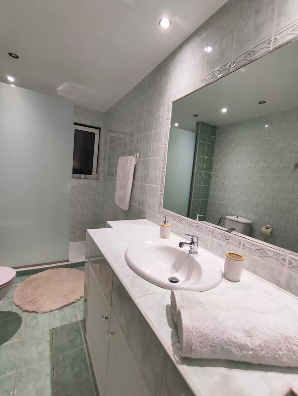 A modern bathroom with a large mirror, a white sink, and a toilet.