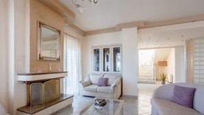 A spacious living room with a fireplace, a sofa, a coffee table, and a large mirror. - Villa Amare - Heraklion Private Garden Retreat (Hersonissos)