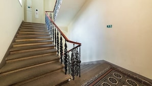 Una escalera con peldaños de madera y barandillas de metal negro ornamentado.