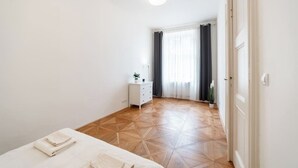 Un dormitorio con cama, mesita de noche, cómoda y ventana con cortinas.