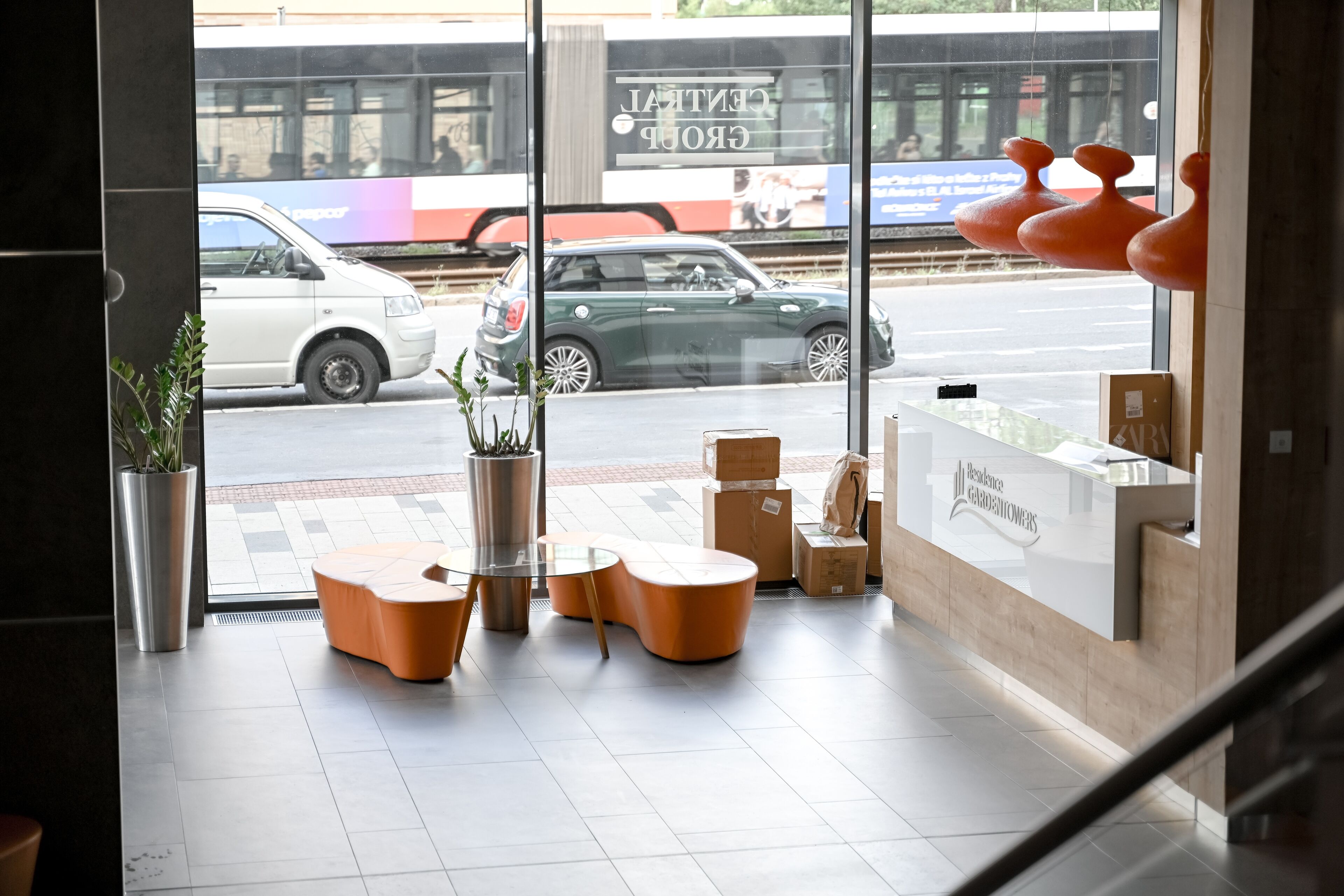 A reception area with a modern design, featuring a reception desk, seating area, and large windows offering a view of the street outside.