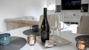 A dining table with a bottle of wine, two glasses, a candle, and a tray with snacks. - Lovely Family Suite (Apart534), Lovely family suite: luxurious modern apartment with private garden (Prague)