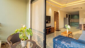 Una sala de estar moderna con un sofá azul, una pequeña mesa de madera con un florero, y una silla de mimbre.