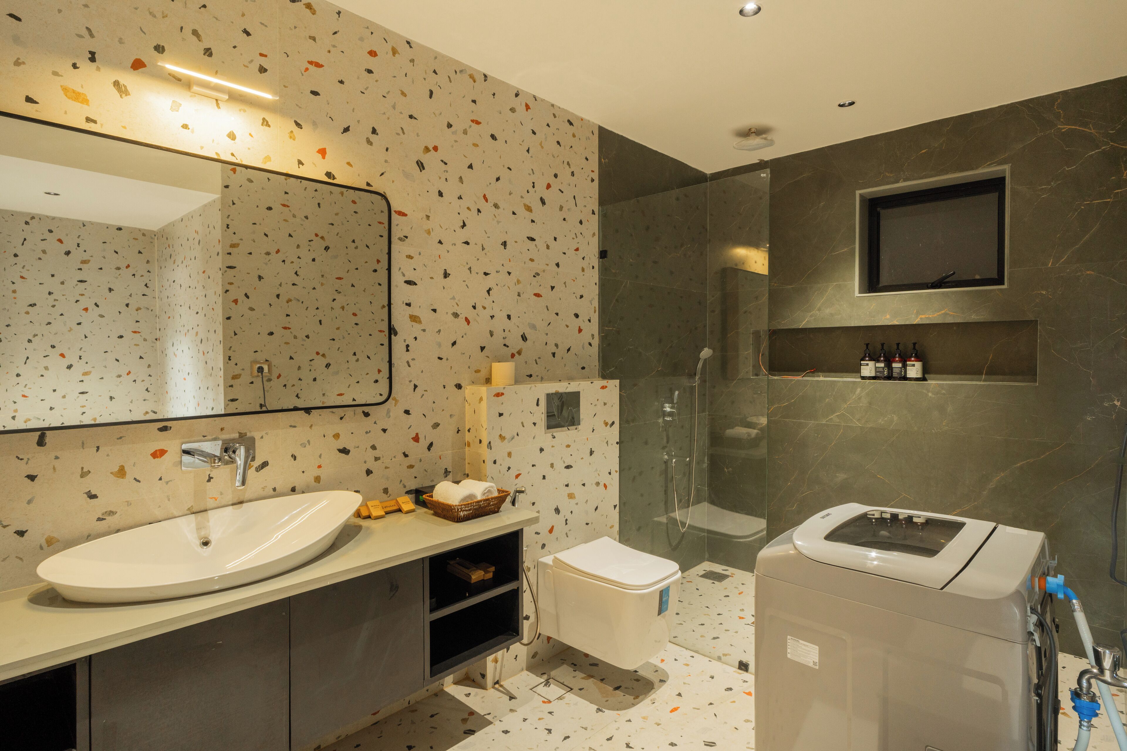 A modern bathroom with a freestanding sink, a toilet, a shower enclosure, and a built-in TV.