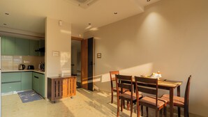 Una cocina moderna con armarios verdes, una mesa de comedor de madera con sillas y una pequeña isla con una tetera.