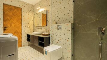 A modern bathroom with a herringbone wood door, a glass shower enclosure, and a white toilet.
