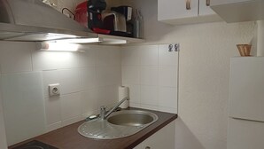 Eine Küche mit Spüle aus Edelstahl, einem eingebauten Herd und weiß gefliesten Wänden.