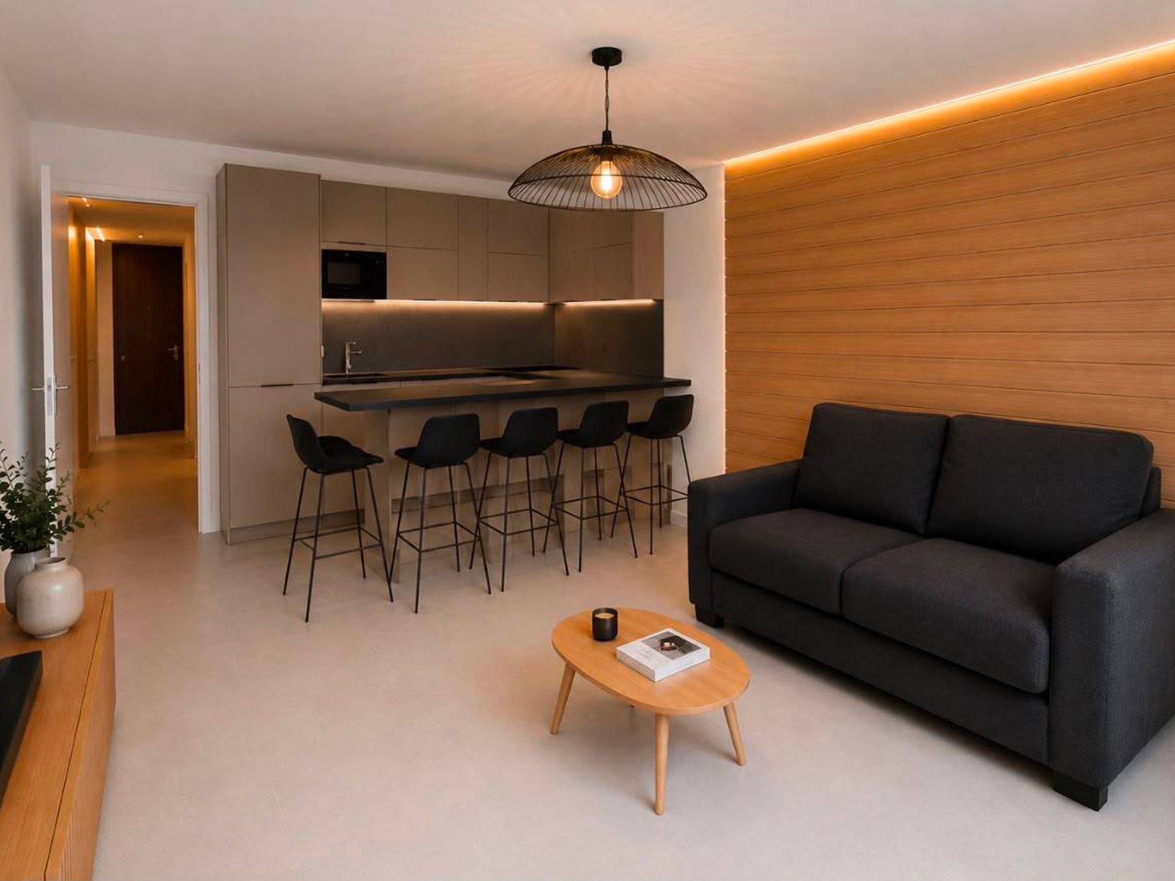 Um espaço de estar moderno com cozinha, balcão, sofá e mesa de centro.