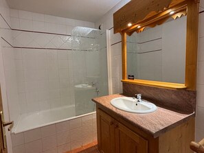 A bathroom with a glass-enclosed shower, a sink, and a wooden vanity. - Bright studio, ski-in ski-out, pets allowed (Les Deux Alpes)