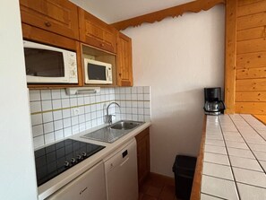 A compact kitchen with wooden cabinets, a microwave, a sink, and a coffee maker. - Bright studio, ski-in ski-out, pets allowed (Les Deux Alpes)