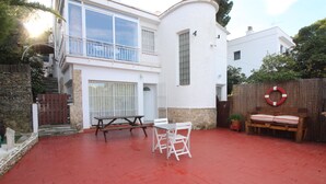 A patio with a picnic table and chairs, a wooden bench, and a lifebuoy on a fence.