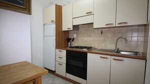 A compact kitchen with white cabinets, a wooden countertop, a sink, and a stove. - 6-Person Beach Apt, Pets Allowed. (Llançà)