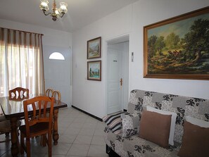Un comedor con una mesa y sillas, un sofá con cojines estampados, y un cuadro en la pared.