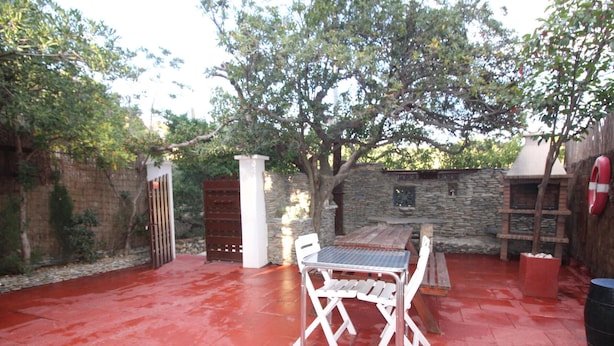 An outdoor patio with a red-tiled floor, a wooden table, and white chairs. - 6-Person Beach Apt, Pets Allowed. (Llançà)