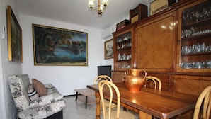 A dining area with a wooden table, four chairs, a sofa, and a painting on the wall. - 6-Person Beach Apt, Pets Allowed. (Llançà)
