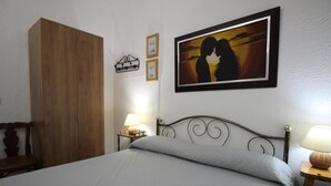 A bedroom with a bed, a wooden wardrobe, a nightstand with a lamp, and a framed picture on the wall. - 6-Person Beach Apt, Pets Allowed. (Llançà)