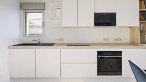 A modern kitchen with white cabinetry, a built-in oven, and a dishwasher. - Beautiful apartment in Touquet, sea view balcony, wifi, box included (Le Touquet-Paris-Plage)
