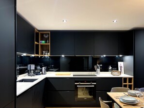 A modern kitchen with black cabinetry, a built-in oven, and a countertop with various appliances.