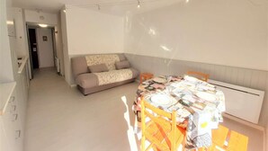 Una stanza luminosa e accogliente con un divano e un tavolo da pranzo per due persone.