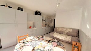 Un ambiente compatto con angolo ristoro, angolo cottura e divano.