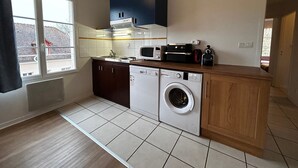 A compact kitchen with a washing machine, microwave, and cabinets. - Renovated apartment near Thermes with pool and Wi-Fi (La Roche-Posay)