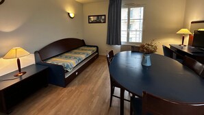 A compact room with a bed, a dining table, and a TV. - Renovated apartment near Thermes with pool and Wi-Fi (La Roche-Posay)