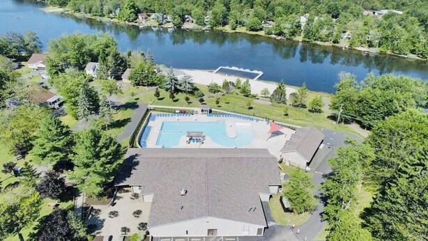 Vue aérienne d’un quartier résidentiel avec une piscine, des maisons et un lac.