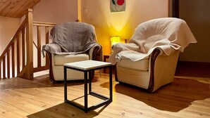 A cozy room with a wooden ceiling, two armchairs, a small table, and a lamp. - Lilas Room in Alleyras - Pets allowed, Guest table, Spacious grounds (Alleyras)