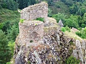 Des ruines de pierre avec une structure circulaire, situées sur une colline et entourées d’une végétation luxuriante.