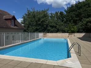 Una piscina rectangular con una cerca metálica blanca y una escalera de metal.