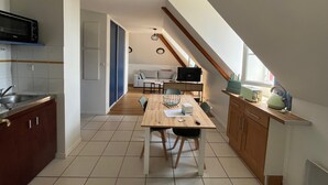 A compact kitchen with a dining area, a microwave, and a dining table with chairs. - Renovated T2 with heated pool near Connétable Spa, parking and WIFI (La Roche-Posay)